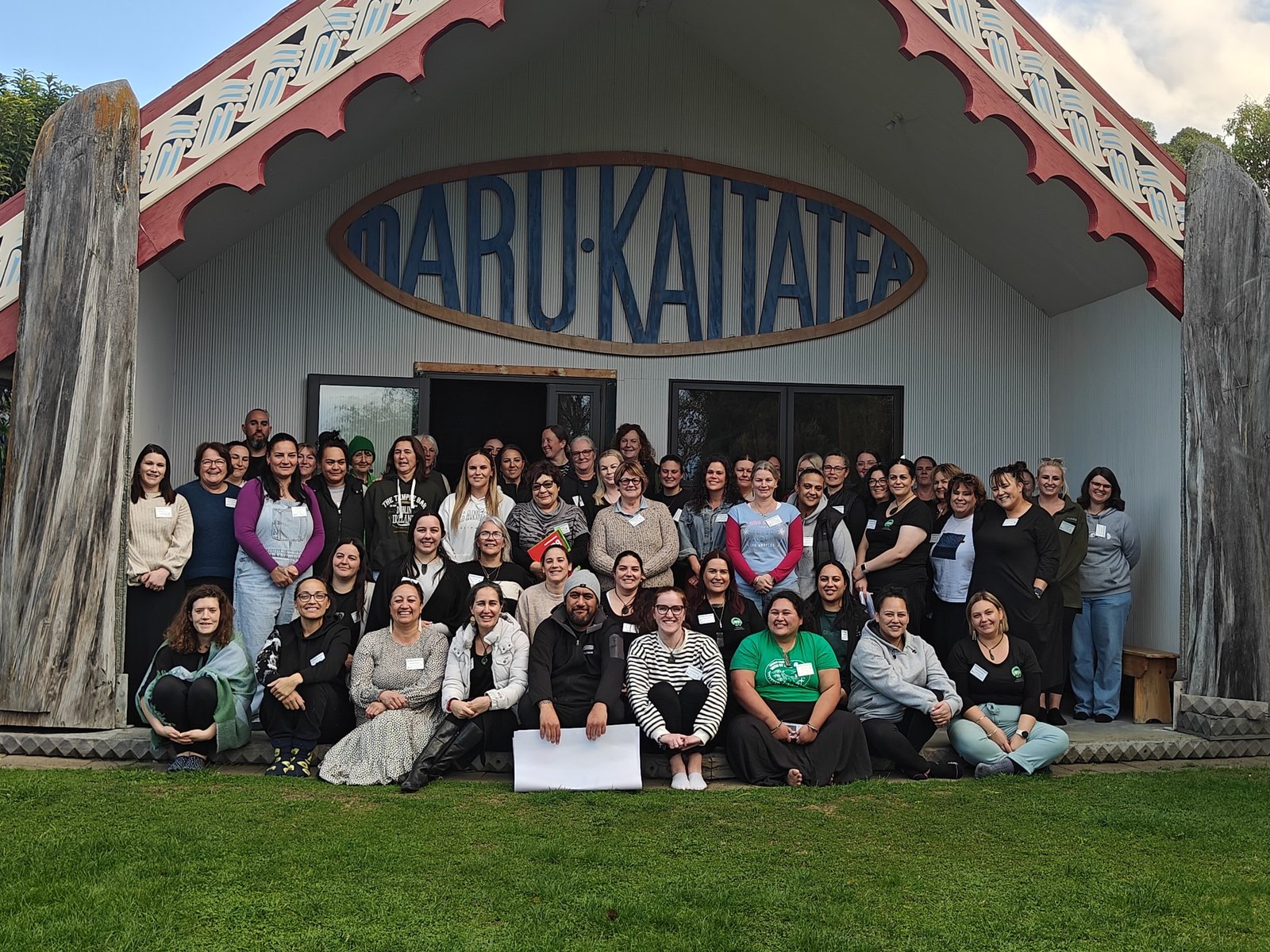 Group of 40 or so people sitting on the porch of Takahanga Marae